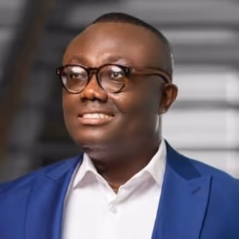 Portrait of a smiling man wearing glasses, a white shirt, and a blue suit jacket.